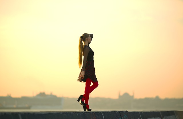 Žena v čiernych šatách a červených silónkach v topánkach na podpätku.jpg