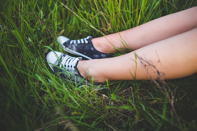 Ženské holé nohy v teniskách, v tráve.jpg